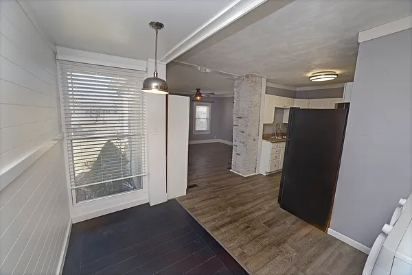 a view of a refrigerator in kitchen and an empty room