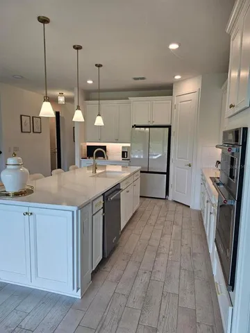 a kitchen with stainless steel appliances granite countertop a sink a stove and a wooden floors