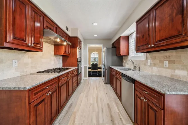 a large kitchen with stainless steel appliances granite countertop a stove a sink dishwasher and a refrigerator