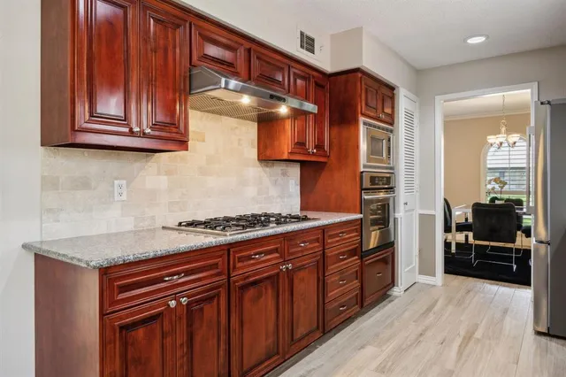 a kitchen with stainless steel appliances granite countertop a stove and a wooden cabinets