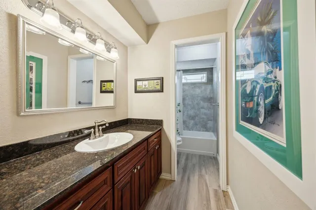 a bathroom with a granite countertop sink a mirror and a shower