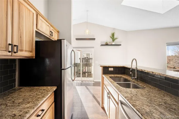 a kitchen with granite countertop a sink a stove and refrigerator