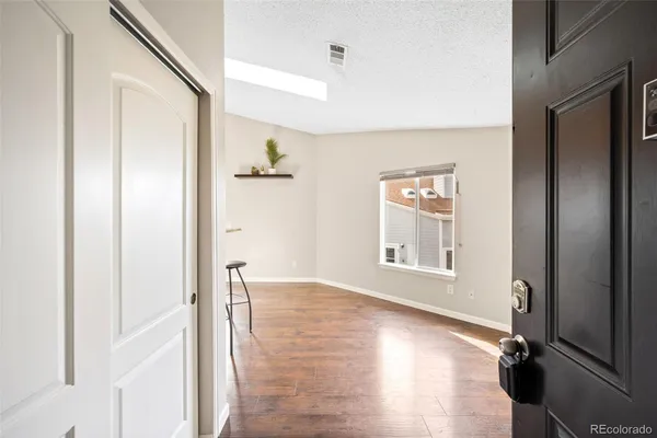 a view of an empty room with wooden floor and a window