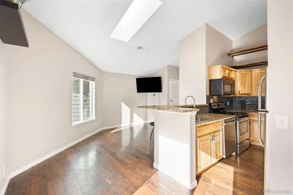 a kitchen with stainless steel appliances a stove top oven a sink a dining table and chairs