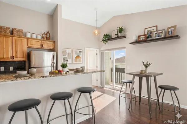 a kitchen with stainless steel appliances kitchen island granite countertop a dining table chairs and a refrigerator