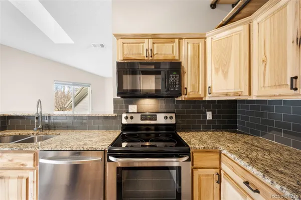 a kitchen with granite countertop a stove top oven microwave and cabinets