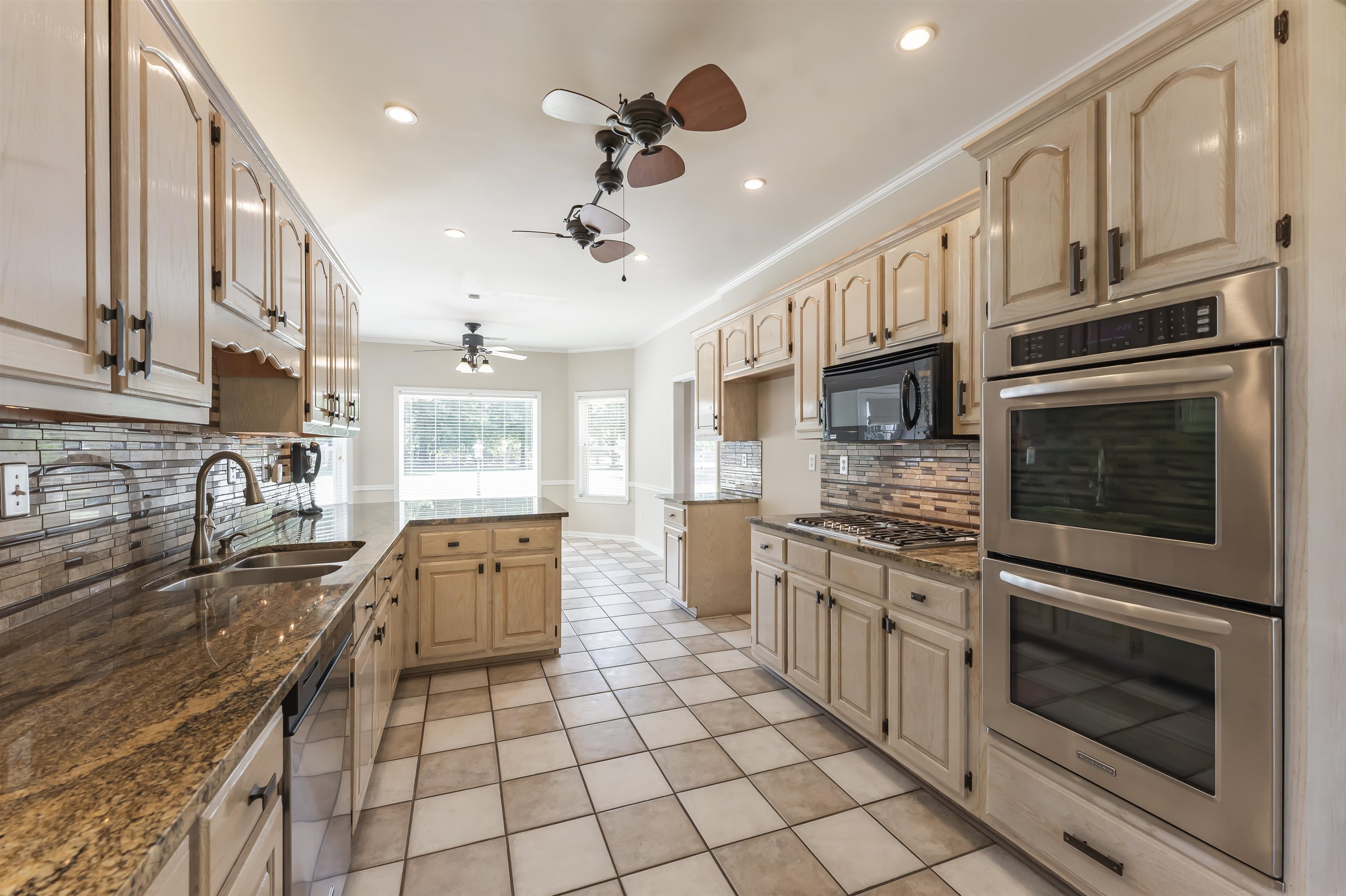 4279 High Plains Road Bartlett, TN 38135 - Photo 2 of 37 Spacious kitchen featuring light wood cabinetry, granite countertops, stainless steel double ovens, a gas cooktop, and a tile backsplash