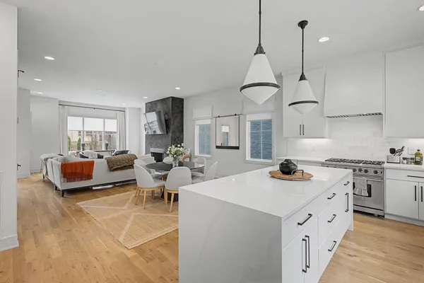 a open kitchen with stainless steel appliances granite countertop a stove a sink dishwasher a refrigerator and white cabinets with wooden floor