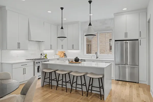 a kitchen with stainless steel appliances granite countertop a dining table chairs refrigerator and sink