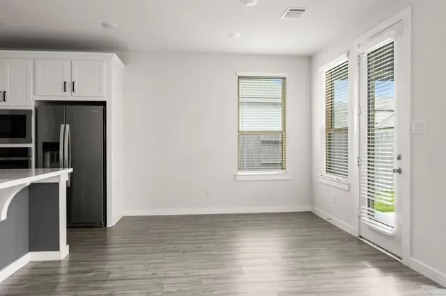 a view of an empty room with a window and wooden floor