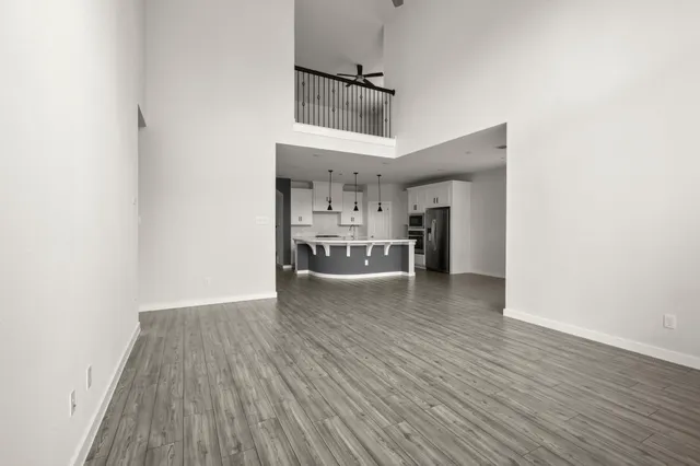 a view of a kitchen and an empty room with wooden floor