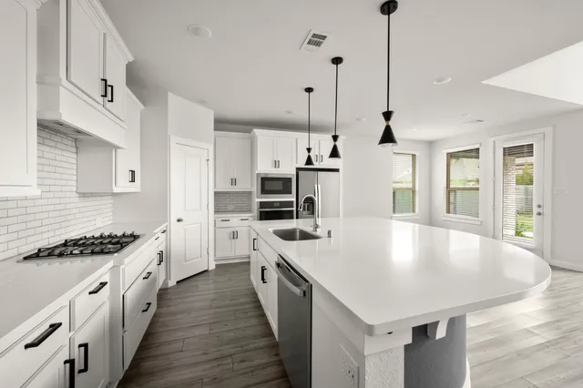 a large kitchen with stainless steel appliances granite countertop a sink a stove and a wooden floors