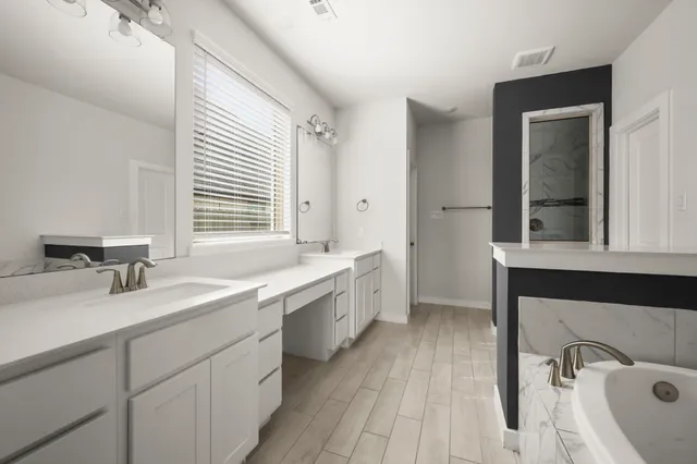 a bathroom with a double vanity sink a mirror and a bathtub