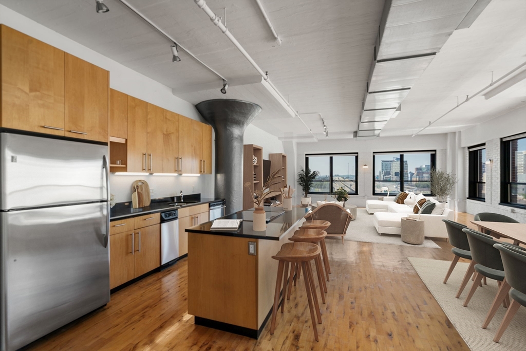 210 Lincoln Street, Unit 601 Boston, MA 02111 - Photo 6 of 29 a kitchen with stainless steel appliances granite countertop a sink dishwasher a refrigerator a stove and a dining table with wooden floor
