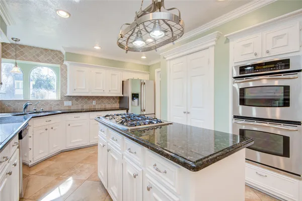 a kitchen with stainless steel appliances granite countertop a stove and a granite counter tops with white cabinets
