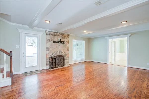 a view of an empty room with wooden floor fireplace and windows