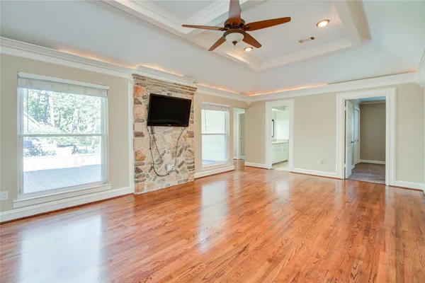 a view of a livingroom with wooden floor a ceiling fan and windows