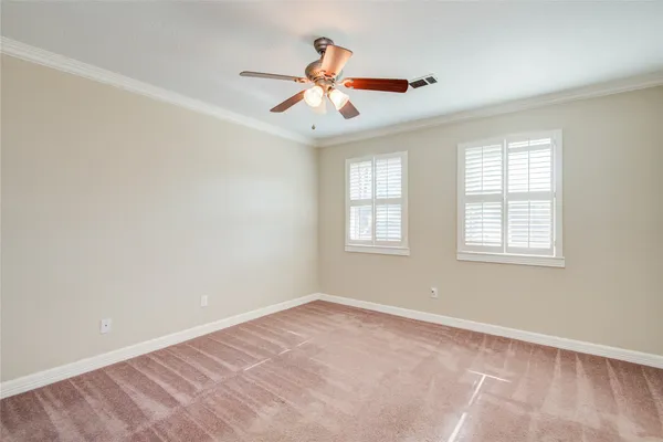 an empty room with chandelier fan and windows
