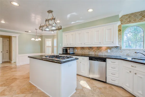 a kitchen with kitchen island granite countertop a sink a stove and cabinets
