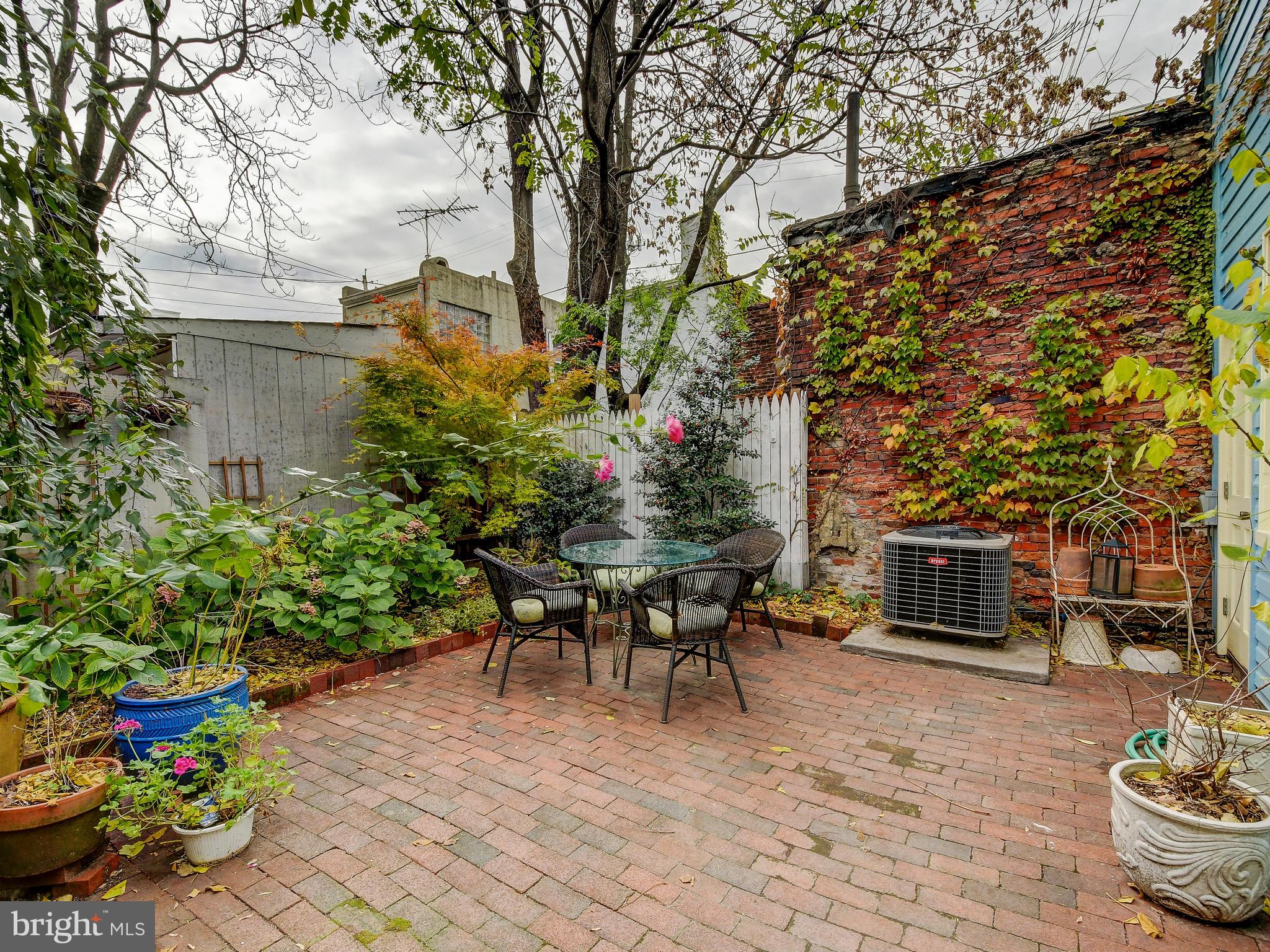 1627 Aliceanna Street Baltimore, MD 21231 - Photo 58 of 60 a backyard of a house with table and chairs potted plants and a large tree