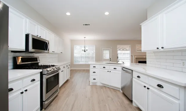 a kitchen with granite countertop a sink cabinets stainless steel appliances and wooden floor