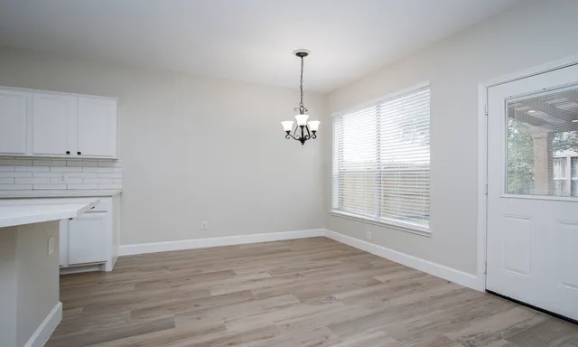 an empty room with wooden floor cabinet and windows
