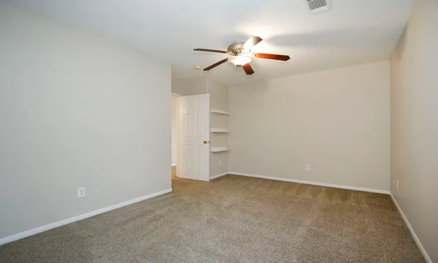 an empty room with closet and a ceiling fan