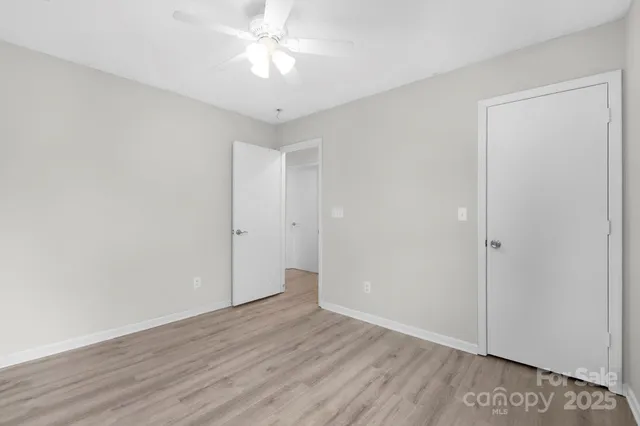 an empty room with wooden floor and ceiling fan