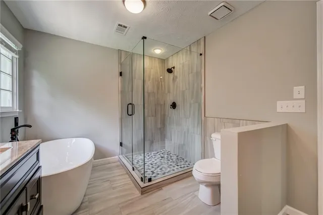 a bathroom with a granite countertop shower a toilet and a sink