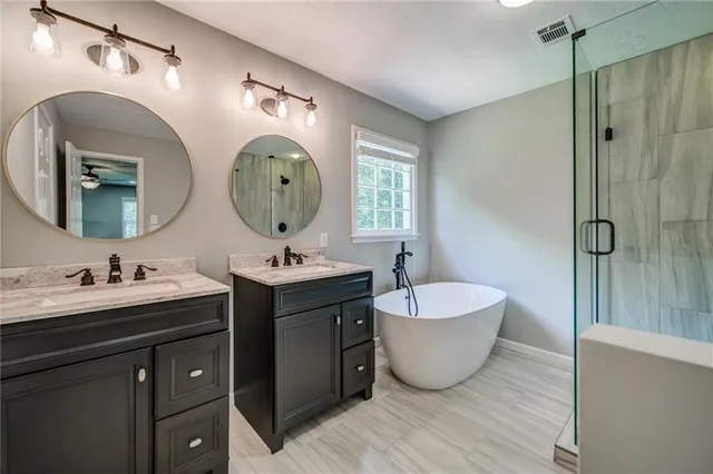 a bathroom with a double vanity sink mirror and bathtub