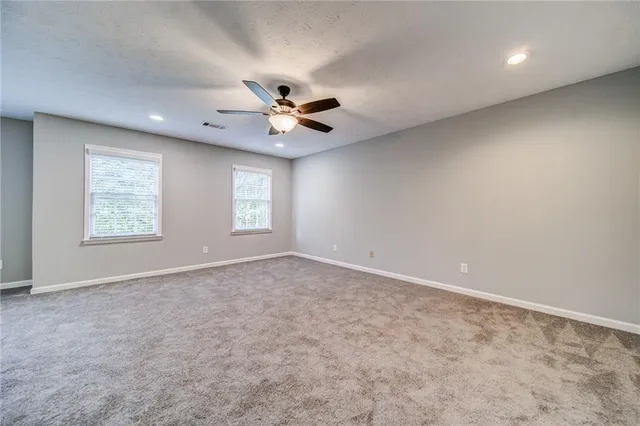 an empty room with windows and ceiling fan