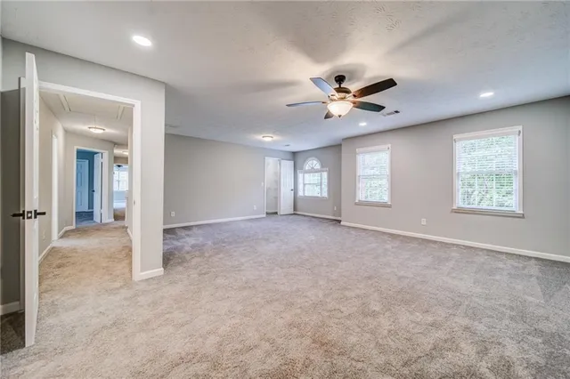 an empty room with chandelier fan and windows