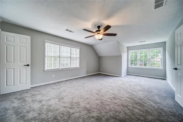 an empty room with windows and ceiling fan