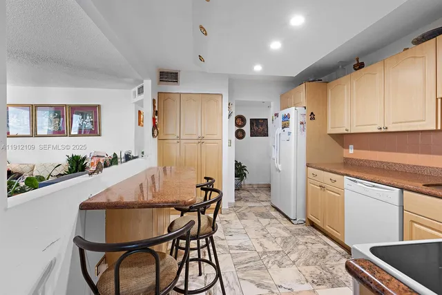 a kitchen with stainless steel appliances a dining table chairs and refrigerator
