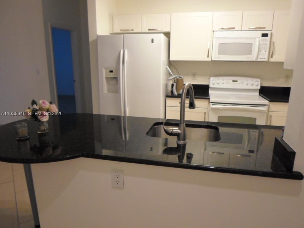 7275 Southwest 90th Way, Unit G 611 Miami, FL 33156 - Photo 44 of 56 a kitchen with stainless steel appliances granite countertop a refrigerator a stove and a sink with wooden floor