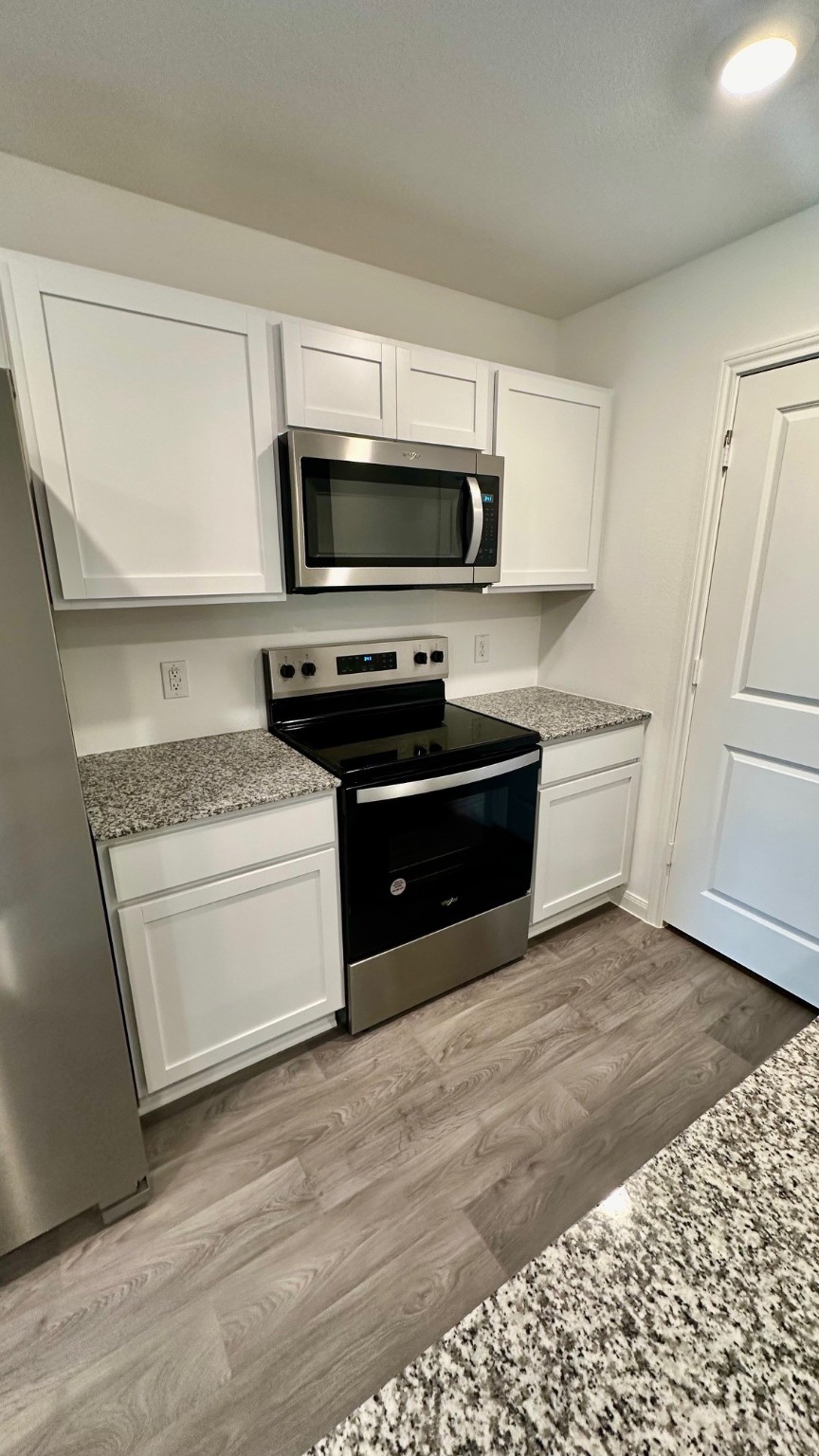 11926 Midas Lane Willis, TX 77378 - Photo 11 of 28 a kitchen with stainless steel appliances granite countertop a stove a sink and a microwave