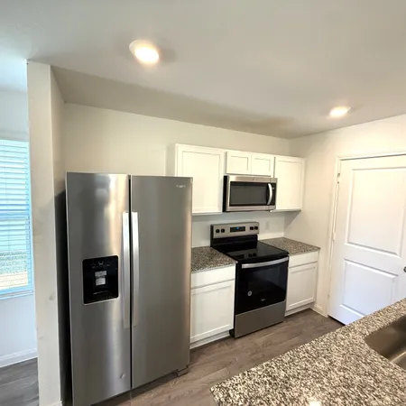 a kitchen with stainless steel appliances granite countertop a refrigerator a sink a stove a microwave and island
