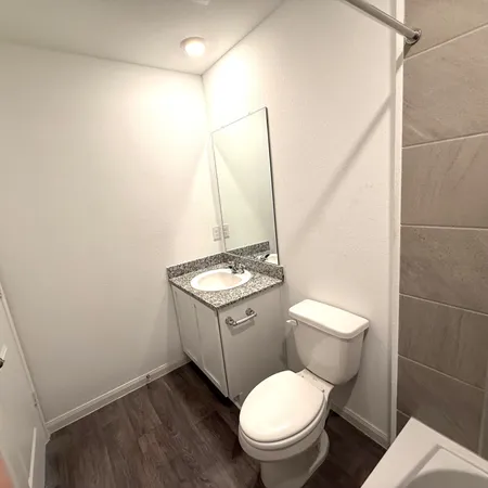 a bathroom with a granite countertop toilet sink and mirror