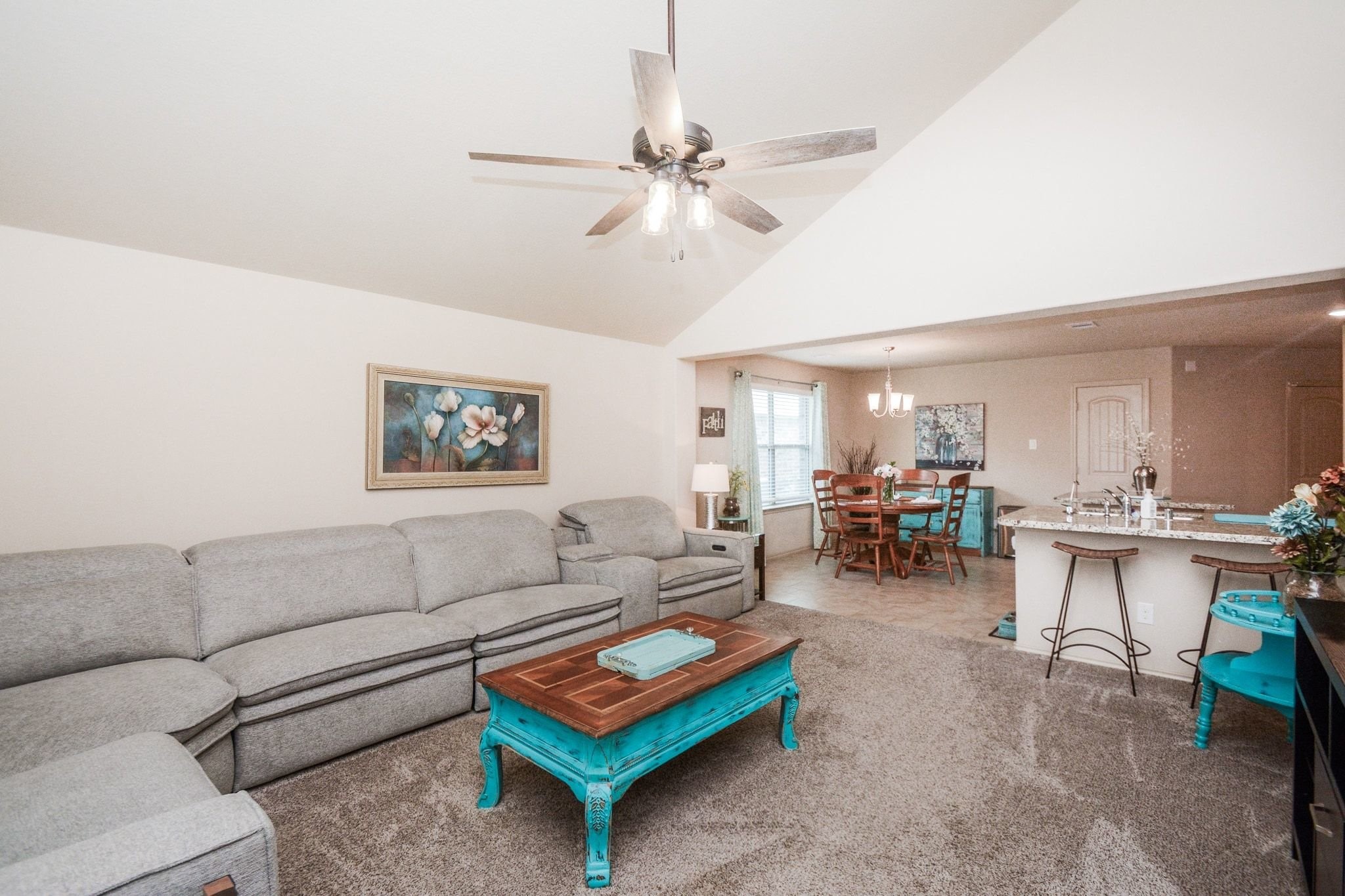 23318 Dukes Run Drive Spring, TX 77373 - Photo 15 of 41 This cozy living space features a vaulted ceiling with a modern ceiling fan. It opens to a dining area and a kitchen bar with seating, creating a welcoming and connected atmosphere.