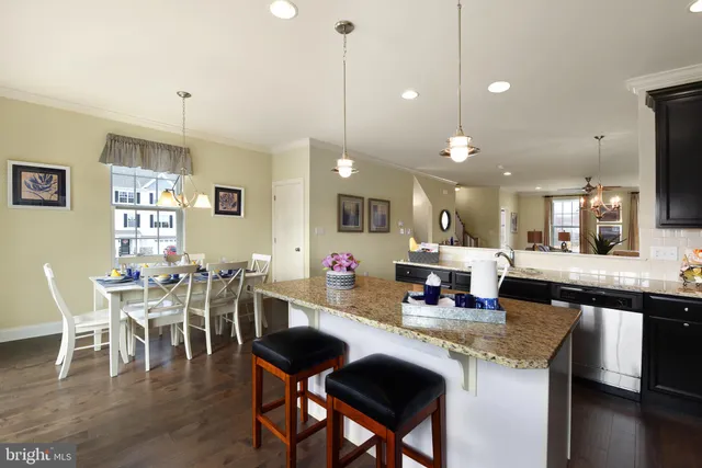 a kitchen with stainless steel appliances granite countertop a stove top oven a dining table and chairs with wooden floor