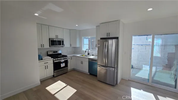 a kitchen with a refrigerator a stove top oven a sink and a potted plant