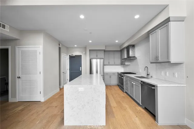 a large kitchen with stainless steel appliances lots of counter space and wooden floor