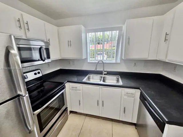 a kitchen with appliances a sink and cabinets