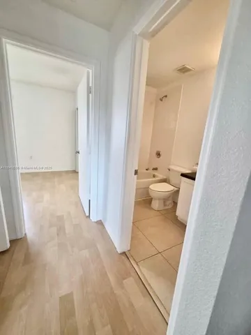 a bathroom with a granite countertop toilet a sink a mirror and bathtub