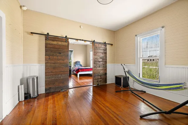 a view of an empty room with window and wooden floor