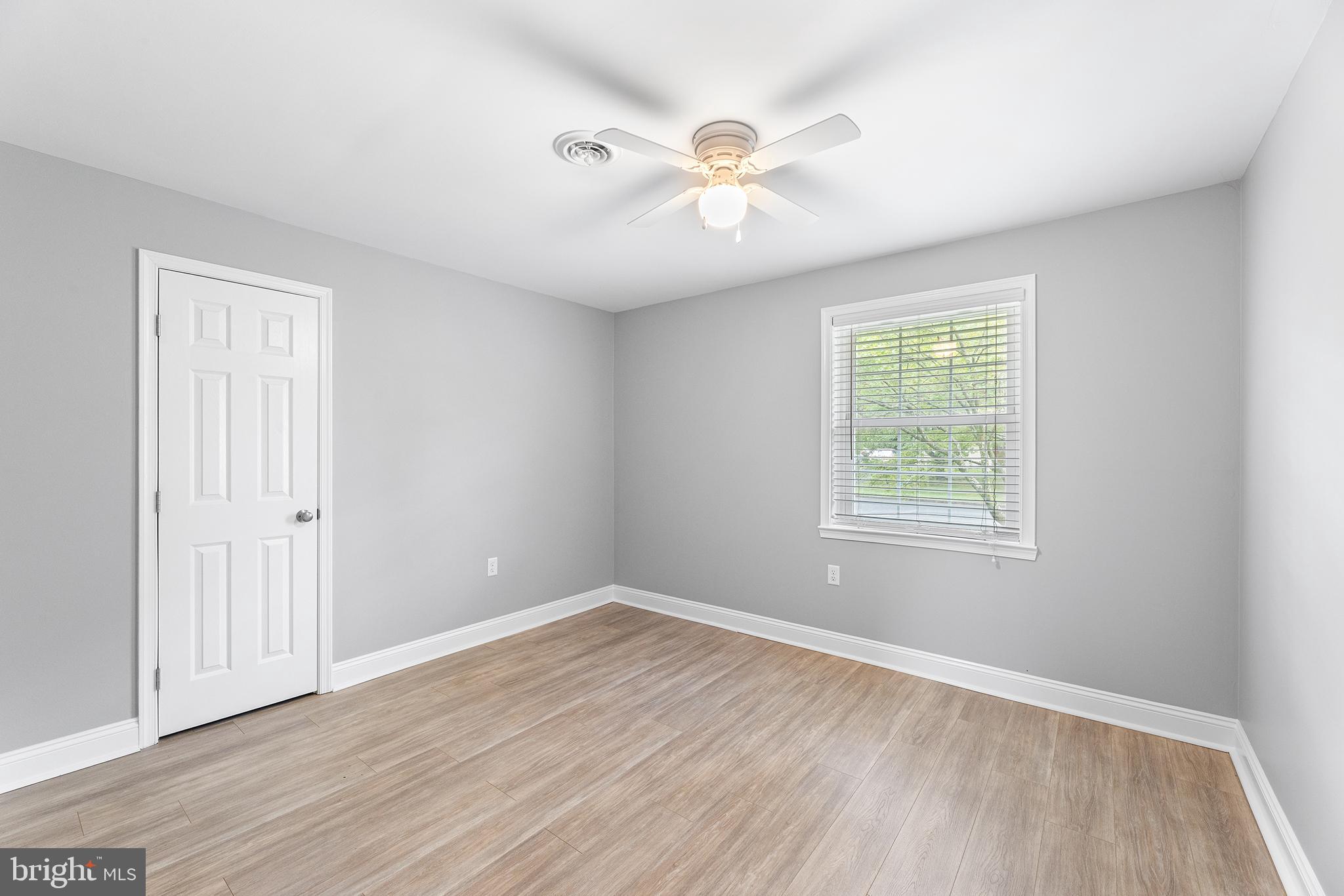 7384 Brett Road Easton, MD 21601 - Photo 19 of 29 an empty room with wooden floor chandelier fan and windows