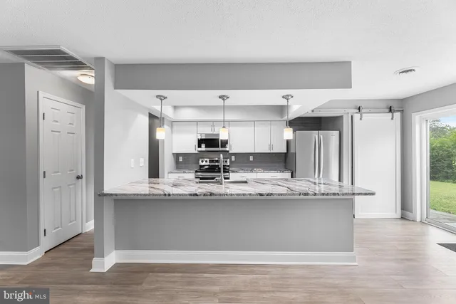 a view of a kitchen with stainless steel appliances granite countertop a sink and cabinets