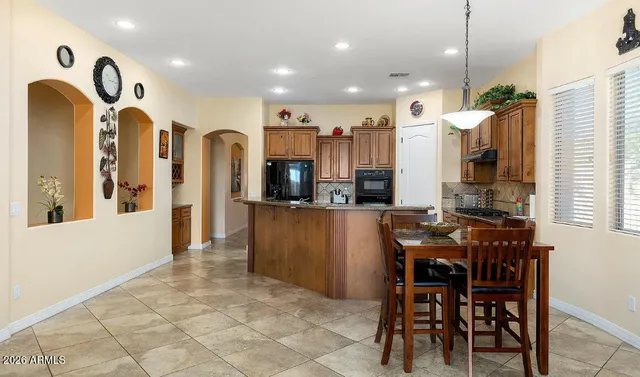 a kitchen with stainless steel appliances kitchen island granite countertop a table and chairs in it