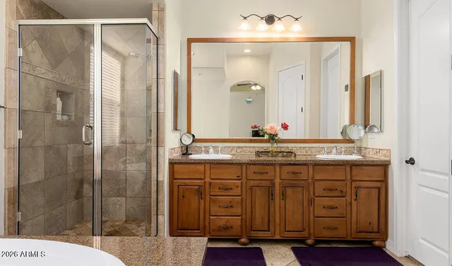 a bathroom with a granite countertop sink a mirror and a shower