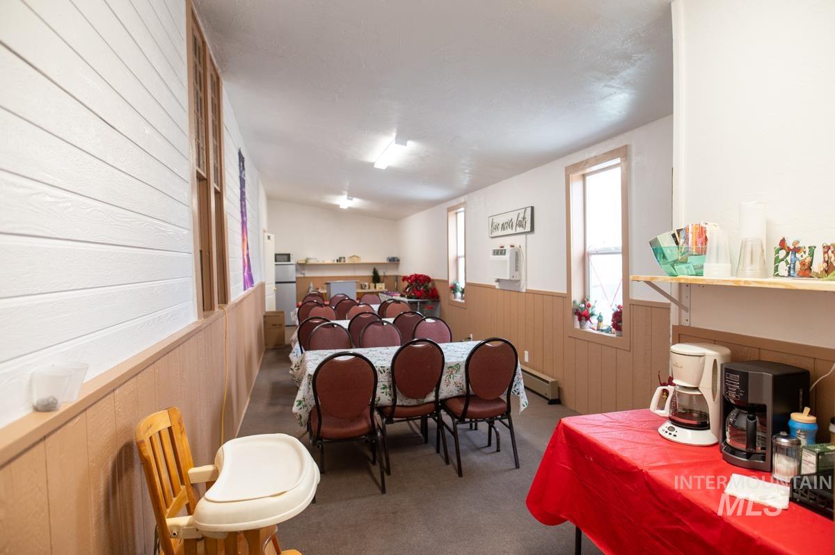 736 East Main Street Weiser, ID 83672 - Photo 9 of 17 Carpeted dining space featuring wooden walls, wainscoting, and a baseboard radiator